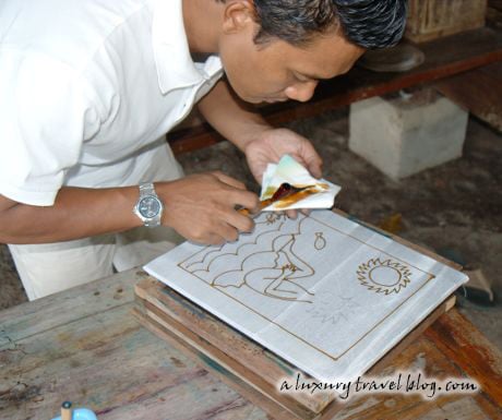 A batik artist draws an outline with hot wax on cotton