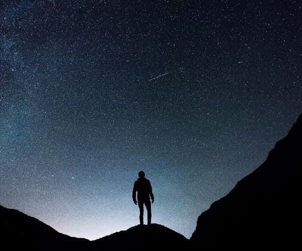 Stargazing in Wales, as man stands on mountain with stars in the sky