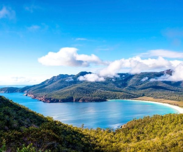 Bay of bright blue water surrounded by green forest and mountain