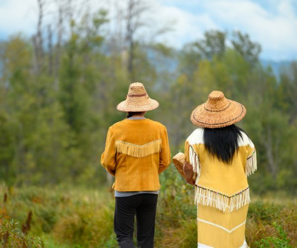 Two First Nations people walking in a forest